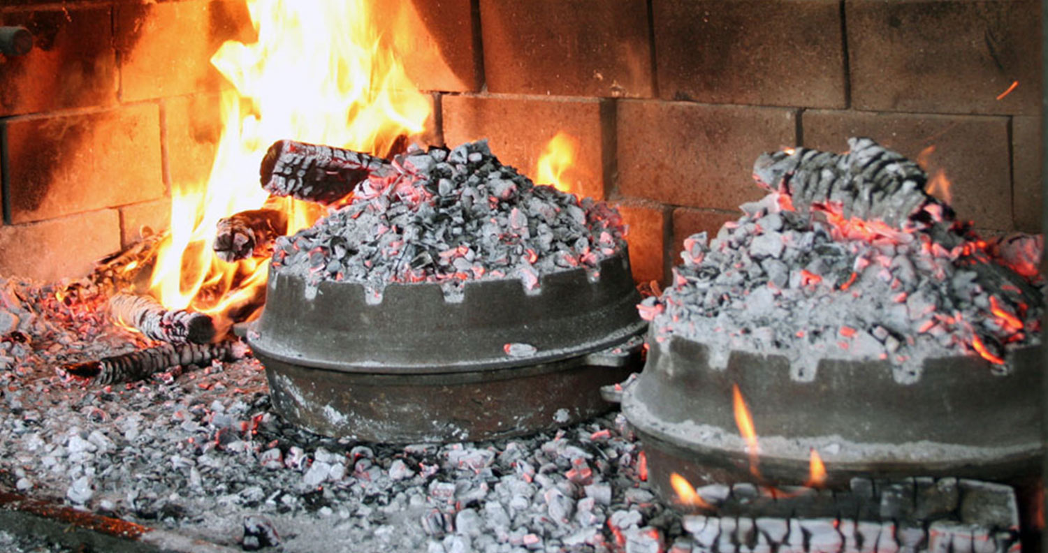 two peka dishes cooking on an open fire